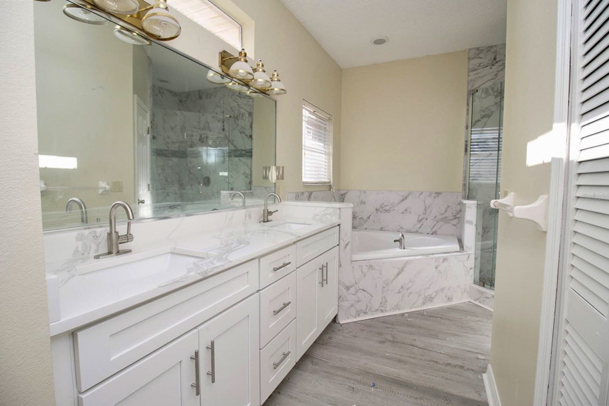bathroom with white cabinets and marble tub